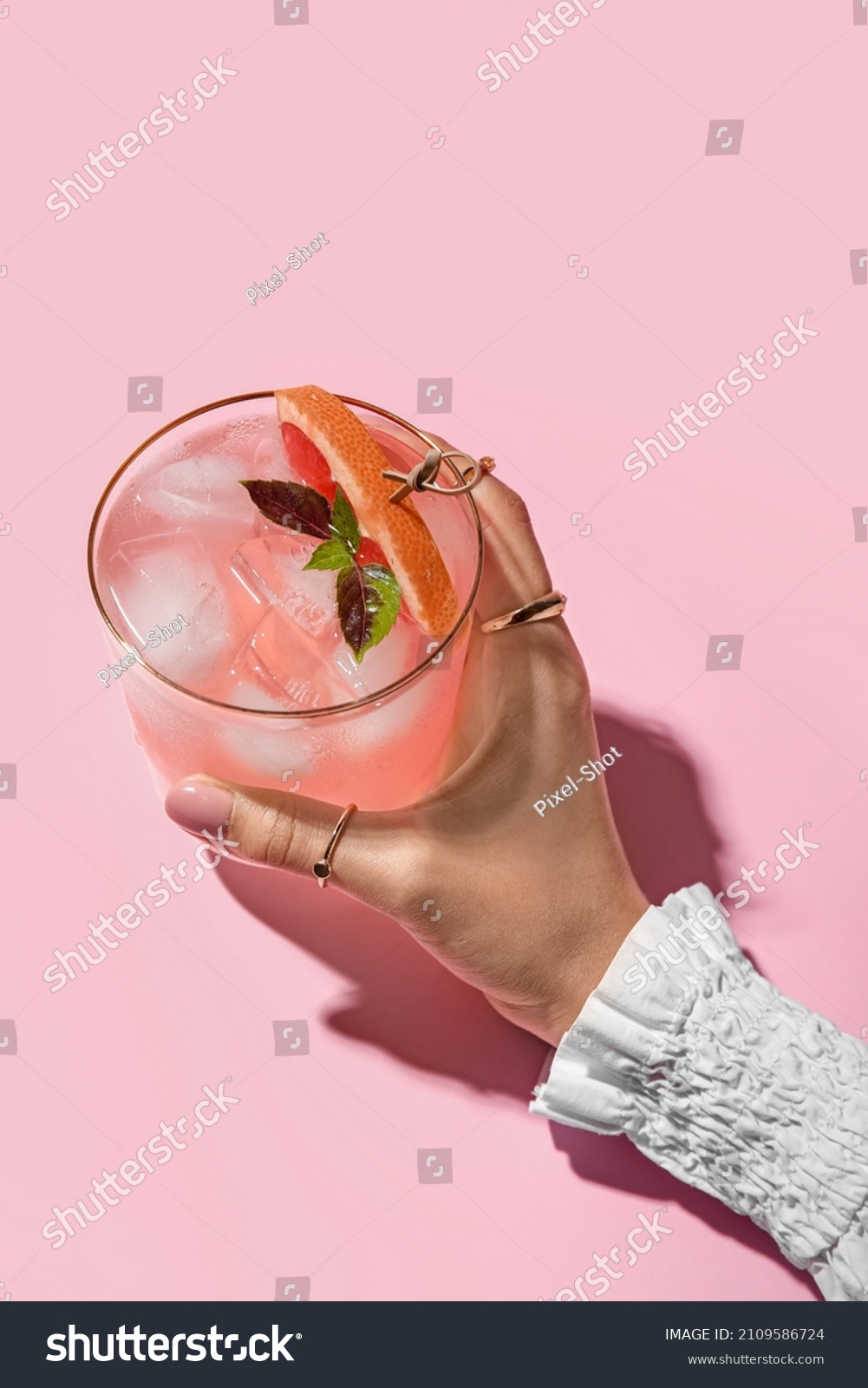 Woman holding glass of tasty grapefruit margarita on color background, closeup #2109586724