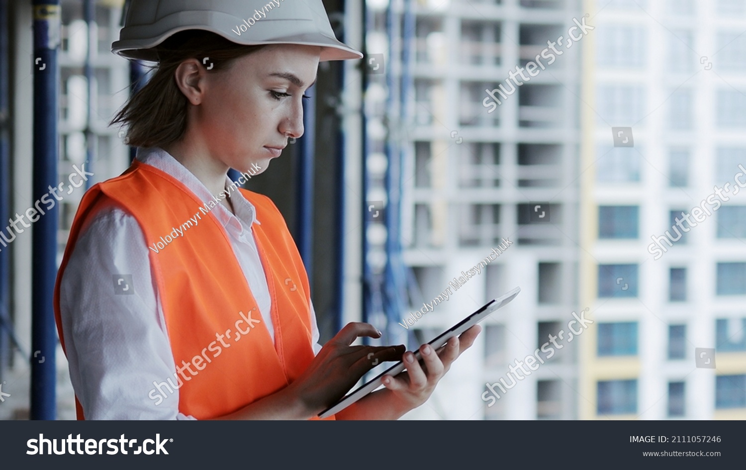 Construction concept of Engineer or Architect working at Construction Site. A woman with a tablet at a construction site. Bureau of Architecture. #2111057246