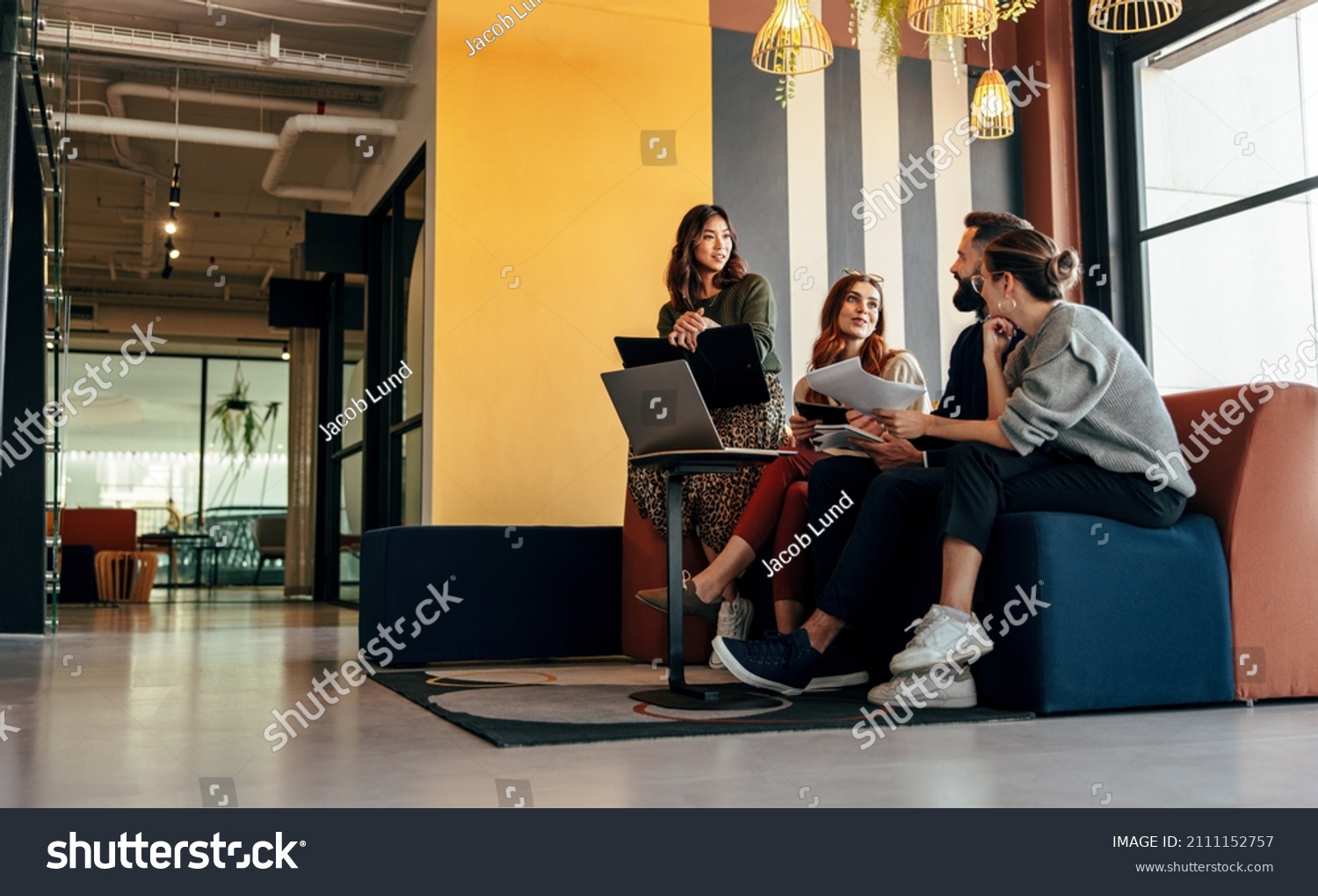Diverse businesspeople working in an office lobby. Group of happy businesspeople having a discussion while sitting together in a co-working space. Young entrepreneurs collaborating on a new project. #2111152757