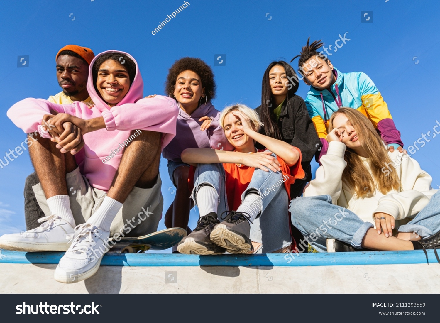 Multicultural group of young friends bonding outdoors and having fun - Stylish cool teens gathering at urban skate park #2111293559