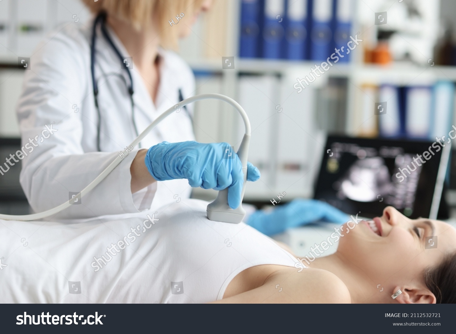 Doctor doing ultrasound examination of breast of patient in clinic #2112532721