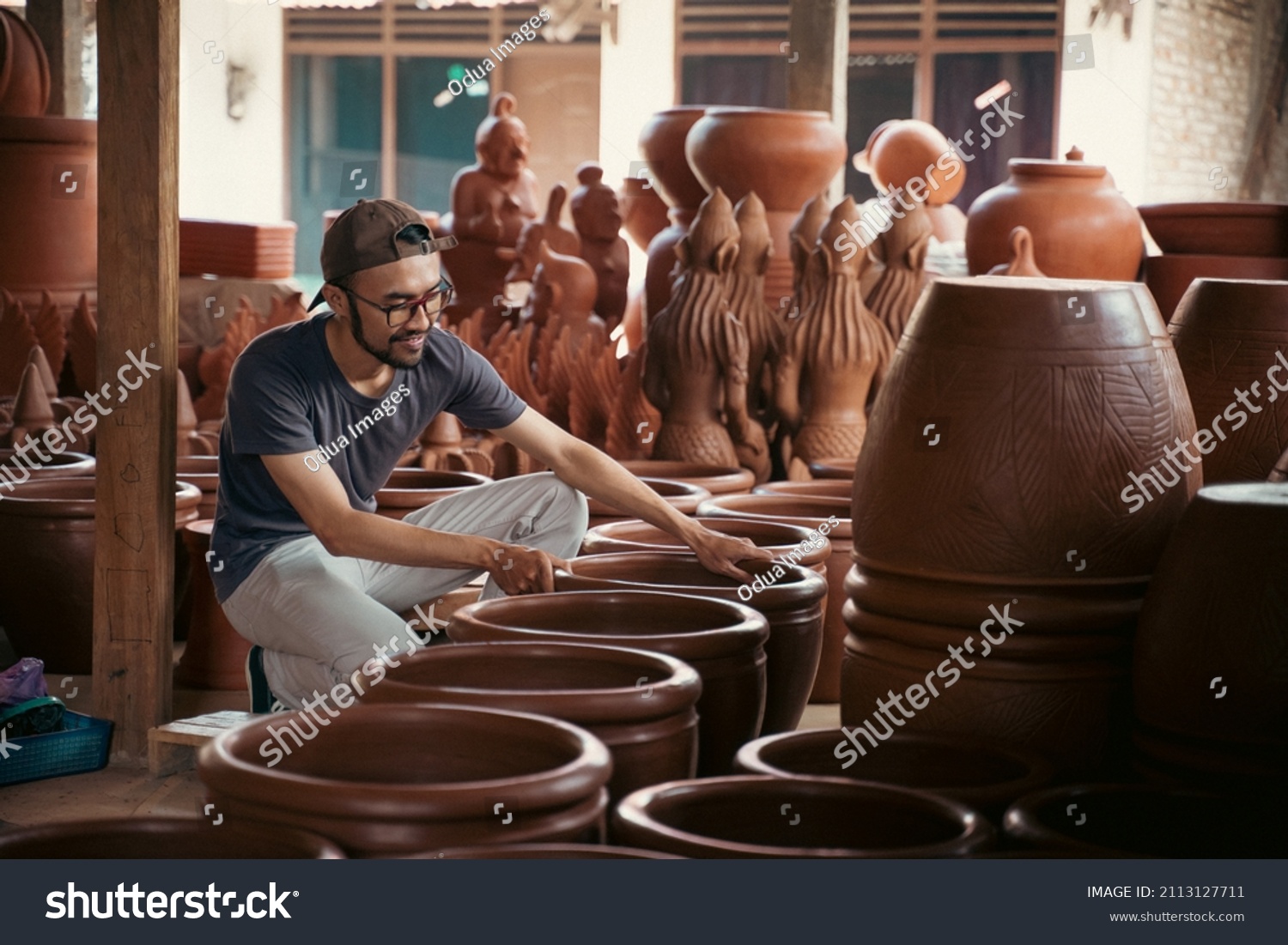 young asian pottery craftsman holding pottery products ready for sale #2113127711