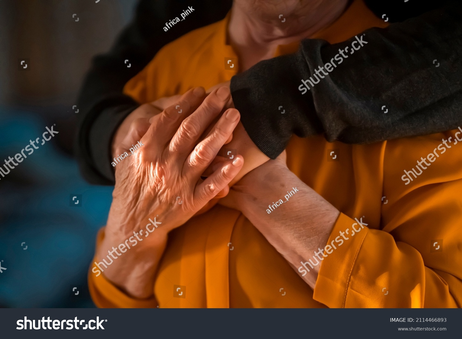 A young man, a volunteer, a son carefully hugs his beloved grandmother, supports and helps an elderly woman in retirement, his grandparent. Young male and female elderly hands with wrinkles closeup.  #2114466893