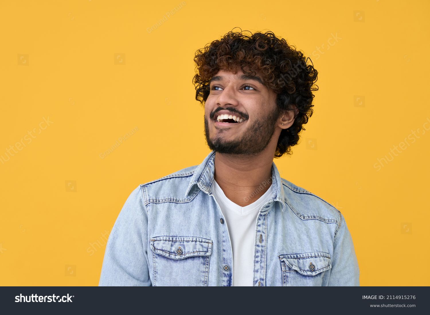 Happy joyful smiling young indian man looking aside up thinking of new good opportunities, dreaming, feeling inspired and proud standing isolated on yellow background. Portrait #2114915276