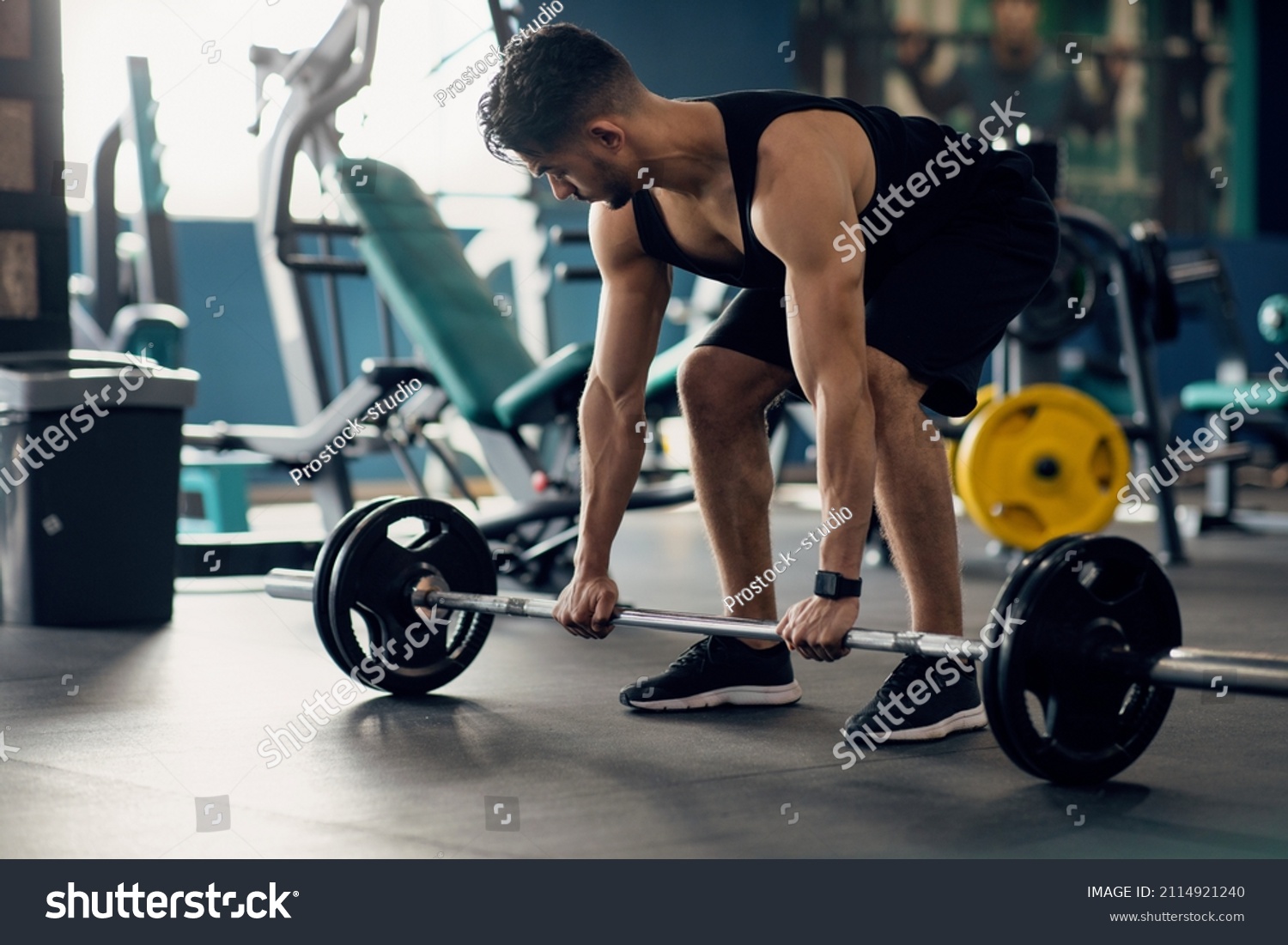 Portrait Of Muscular Middle Eastern Guy Making Deadlift Workout At Modern Gym, Young Arab Male Athlete Lifting Heavy Barbell At Sport Club Interior, Training Muscle Endurance, Closeup Shot #2114921240