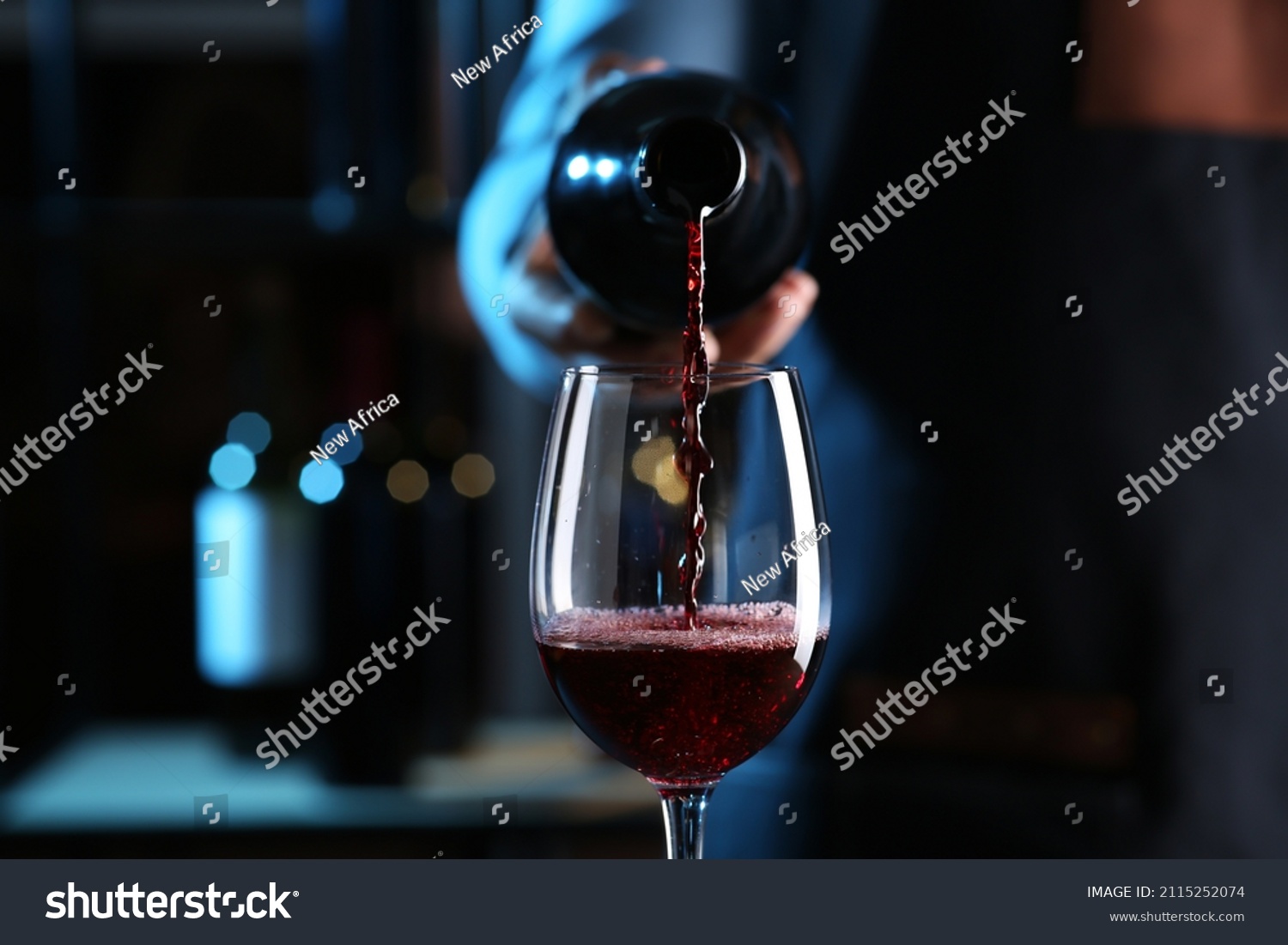 Bartender pouring red wine from bottle into glass indoors, closeup #2115252074