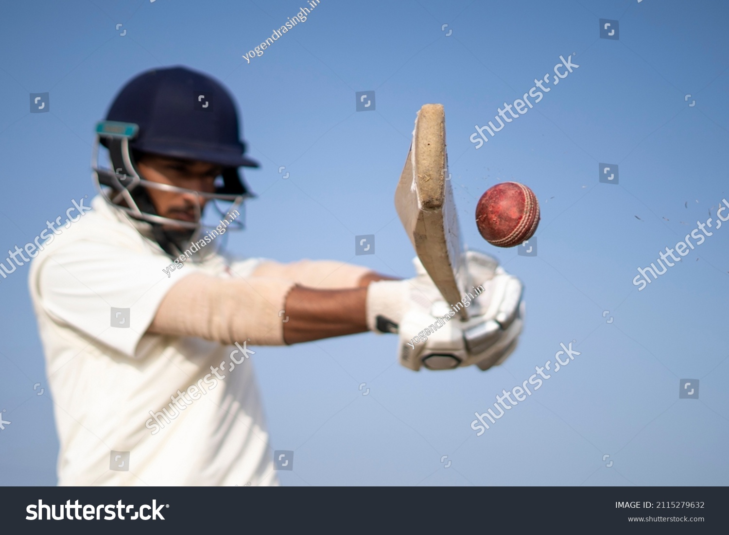 A cricketer playing cricket on the pitch in white dress for test matches. Sportsperson hitting a shot on the cricket ball. #2115279632