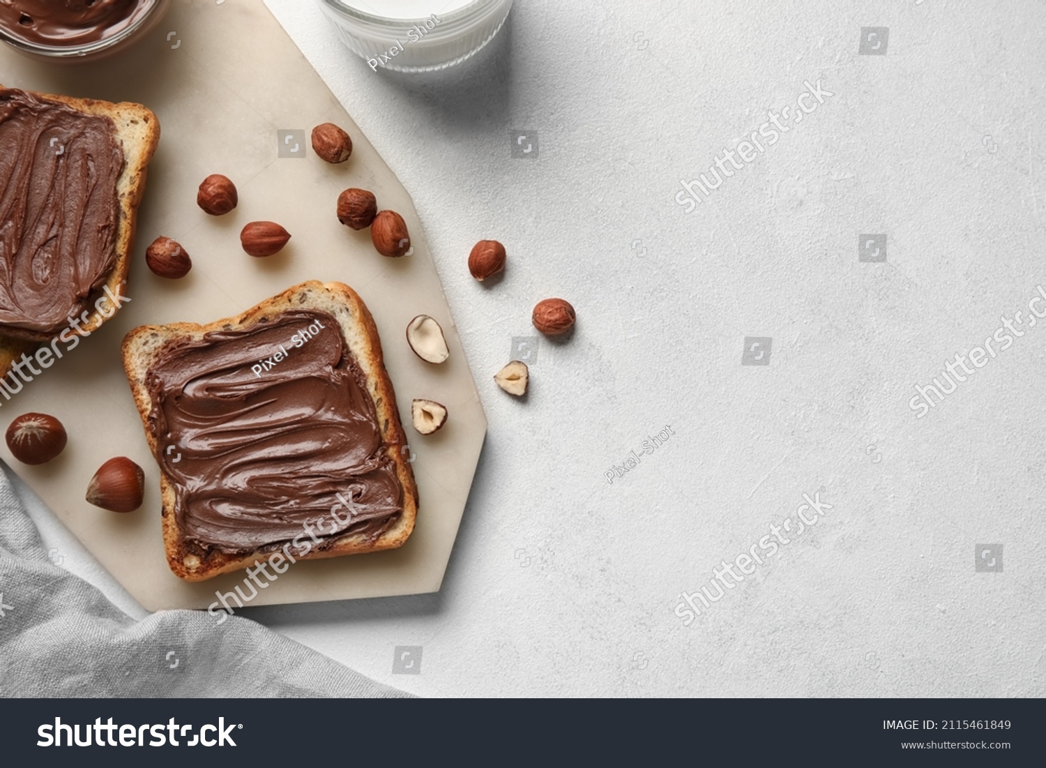 Board of bread with chocolate paste and hazelnuts on white background, closeup #2115461849