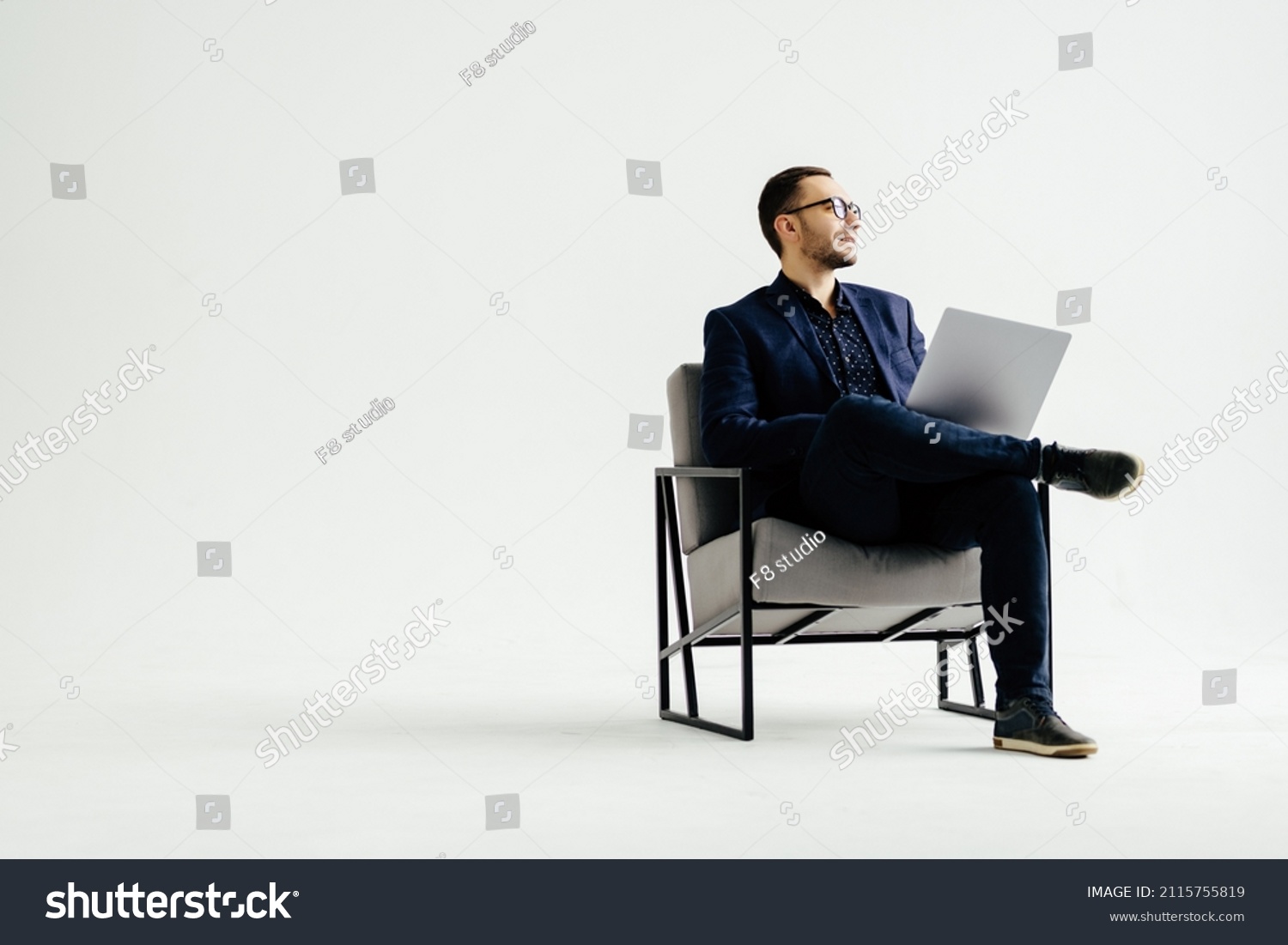 Young smiling businessman sitting in office chair and working on laptop computer isolated on white background #2115755819