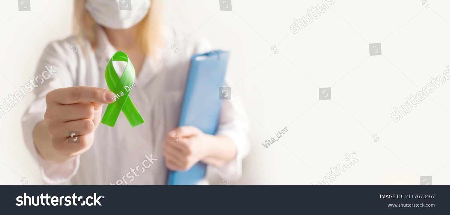 World bipolar day. Doctor in white coat holds green ribbon. Mental health awareness day, Depression, Cerebral palsy. World kidney day. banner. copy space. #2117673467