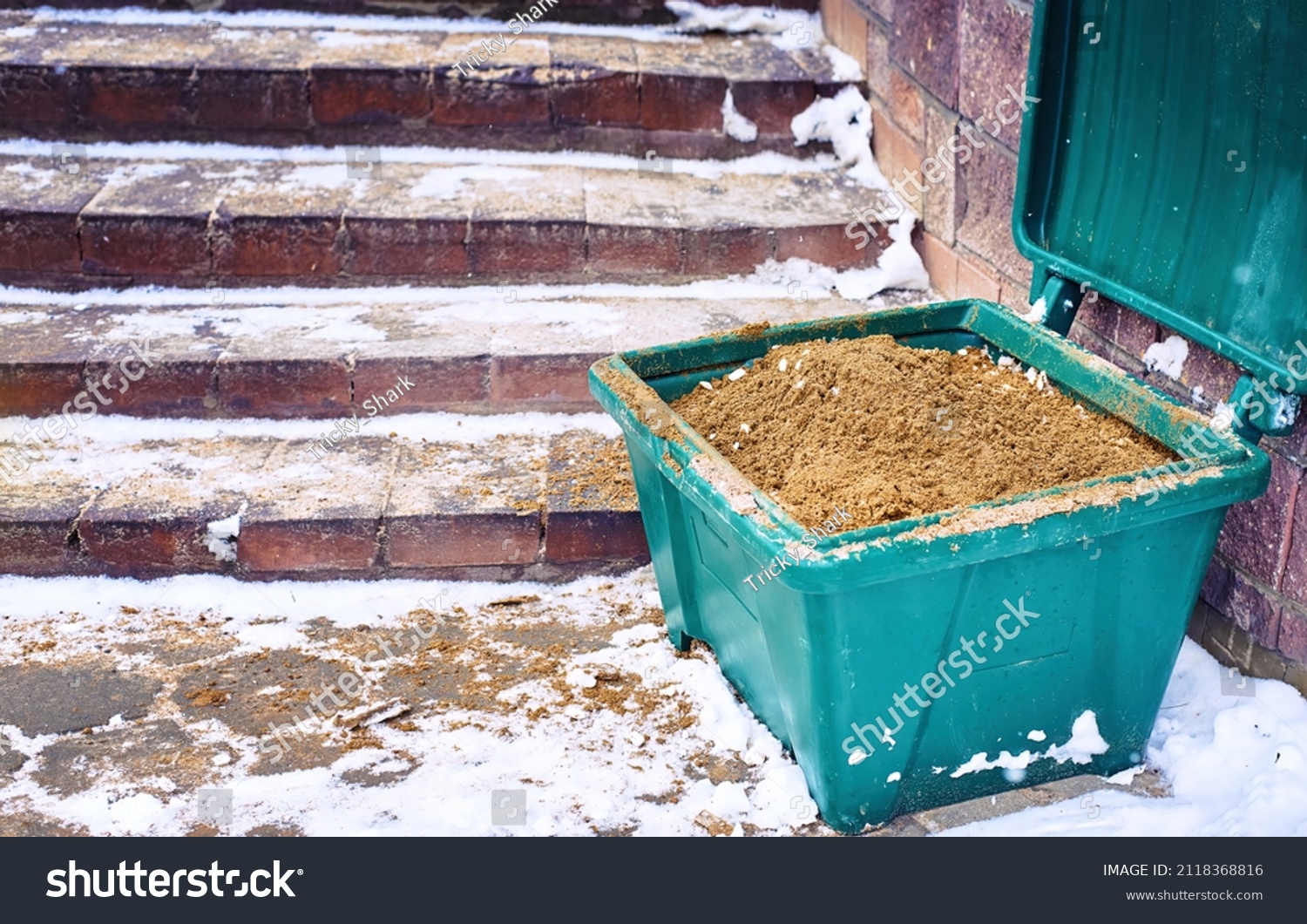 Grit bin, sand for improve traction on snowy and icy steps during winter season. Green plastic grit container, road maintenance in winter. Container with gritting material, prevention slippery surface #2118368816