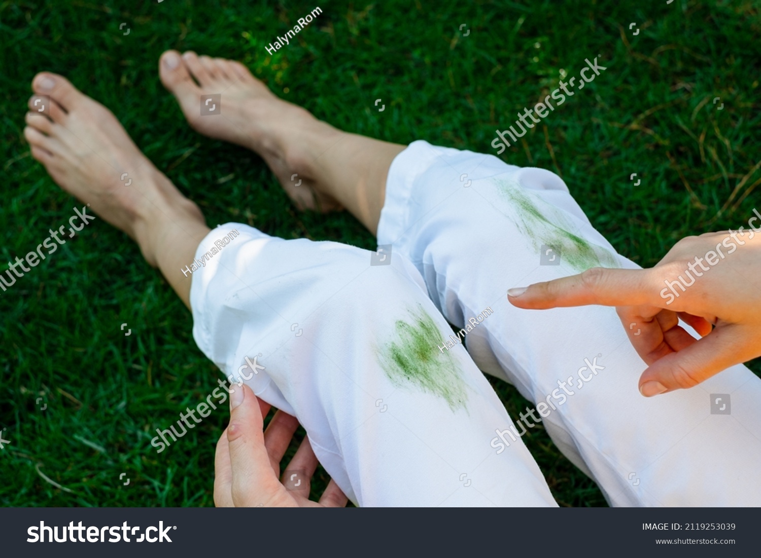 Hand showing dirty stain of grass on white pants from unexpected accident. top view. daily life stain concept. outodoors #2119253039