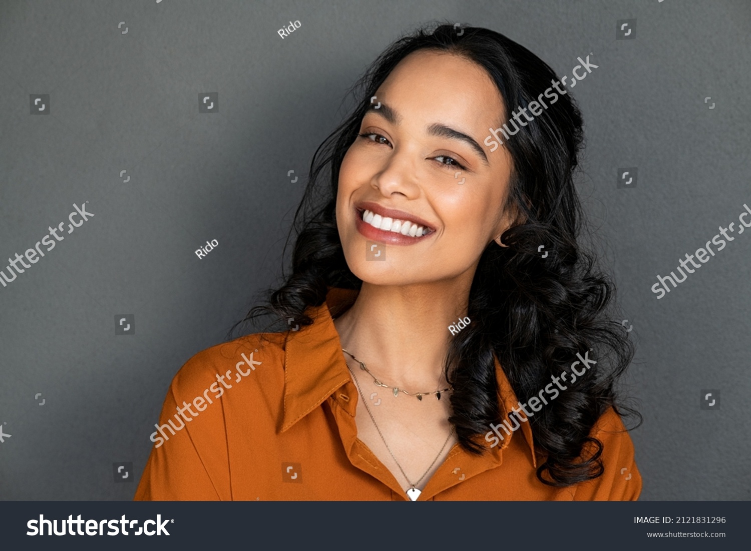 Close up face of young woman with beautiful smile isolated on grey wall with copy space. Successful multiethnic girl. Latin woman looking at camera against gray wall with a big whitening teeth smile. #2121831296