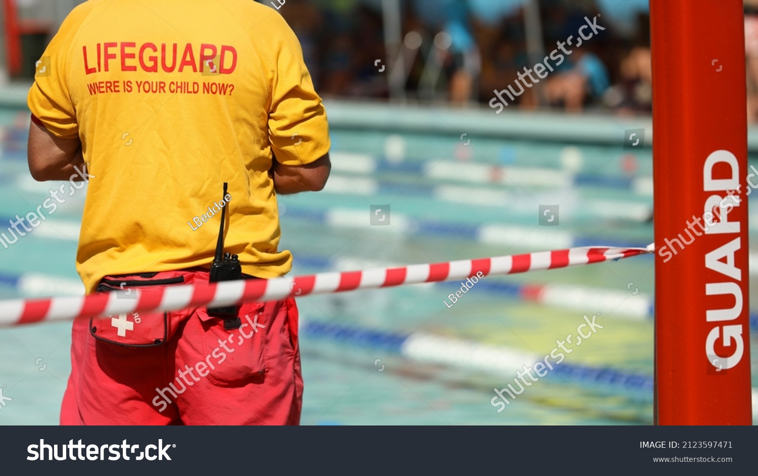 A public pool life guard or pool safety officer in uniform standing duty or guard supervising swimming and children preventing drowning accidents.  #2123597471