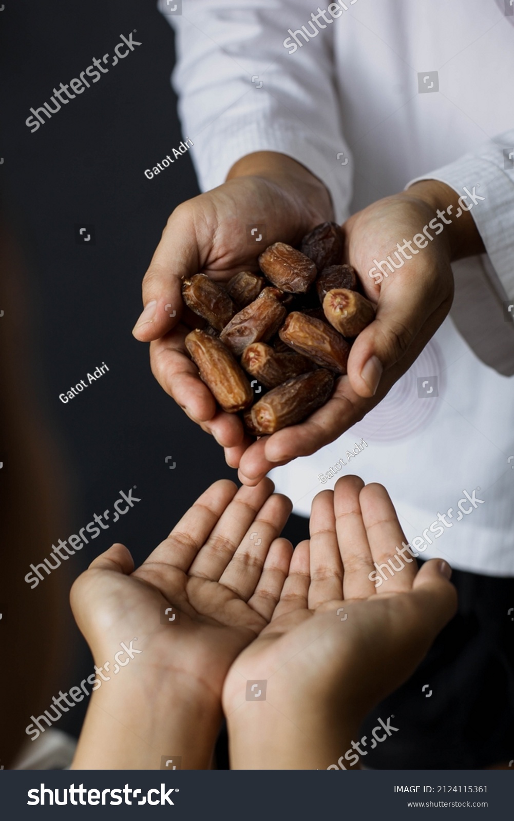 Muslim hands share a fistful of dates. ramadan kareem concept #2124115361