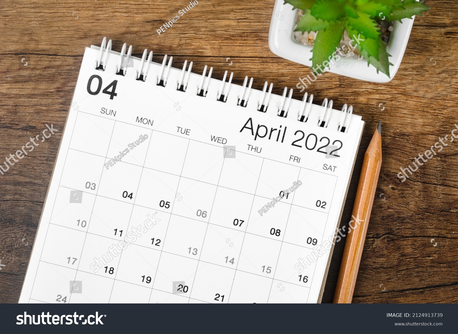 The April 2022 desk calendar with plant on wooden table. #2124913739