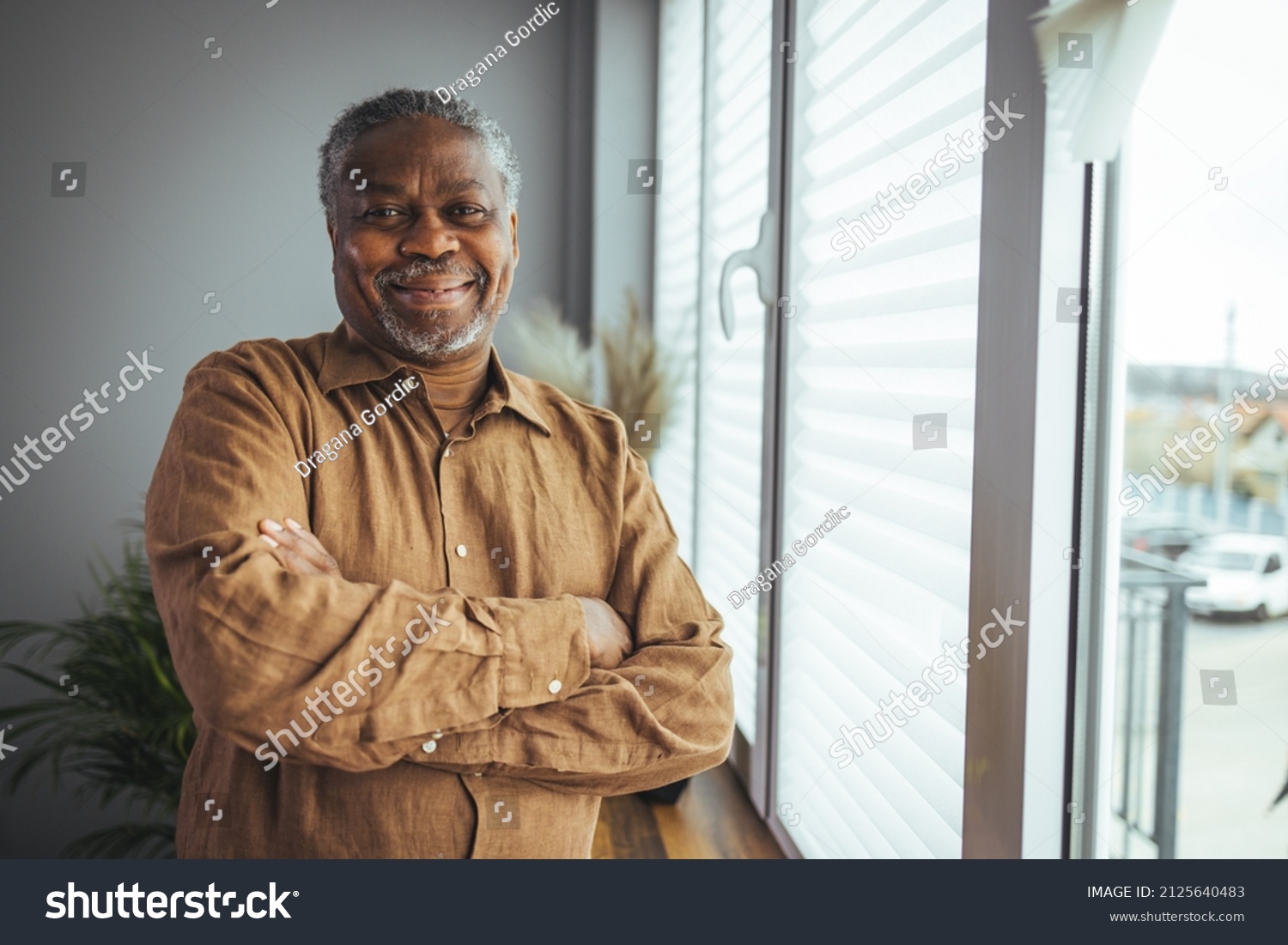 African American Senior Man at home Portrait. Smiling senior man looking at camera. Portrait of black confident man at home. Portrait of a senior man standing against a grey background #2125640483