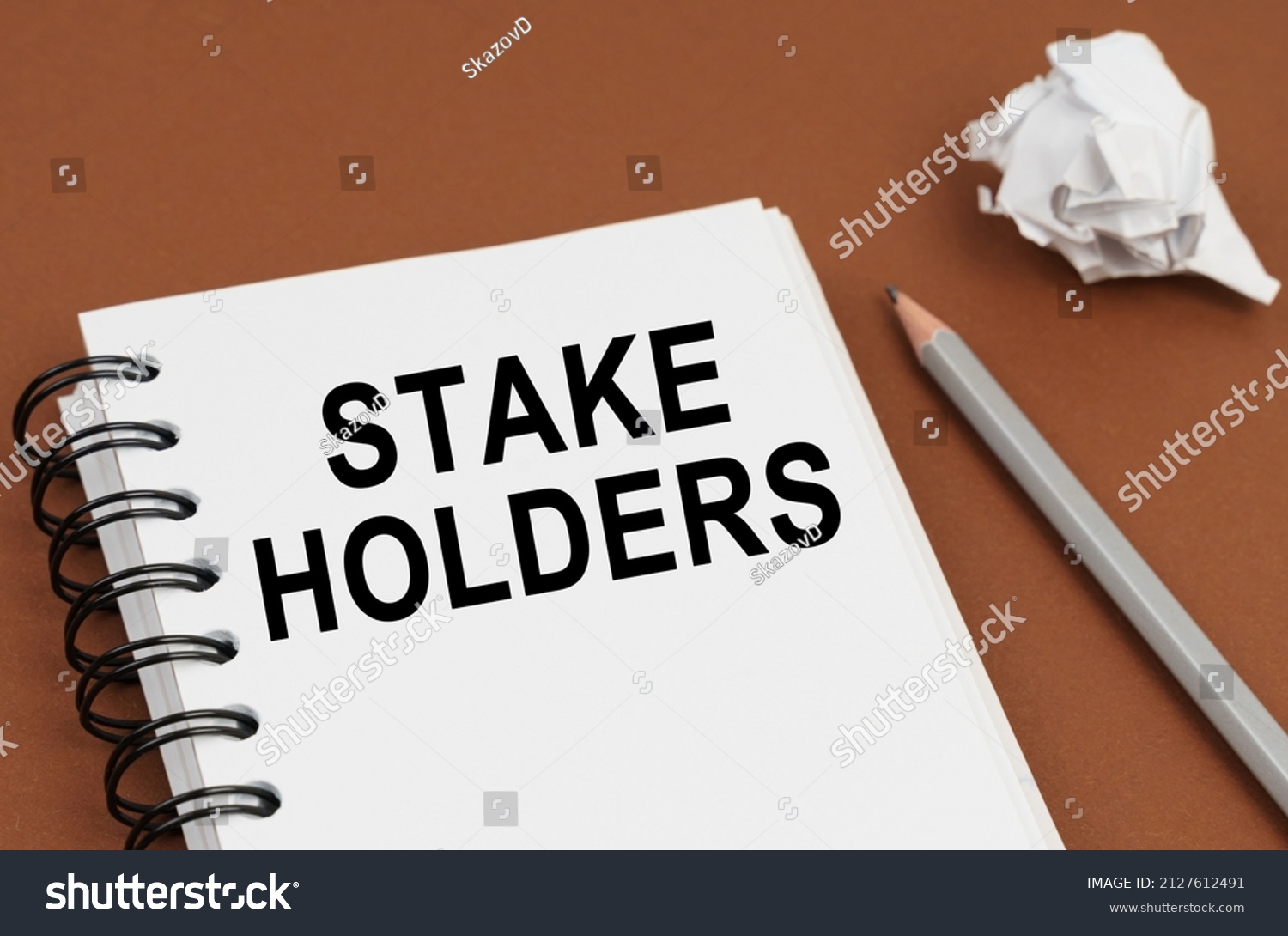 Business and finance concept. On a brown surface lies a pen, crumpled paper and a notepad with the inscription - STAKE HOLDERS #2127612491