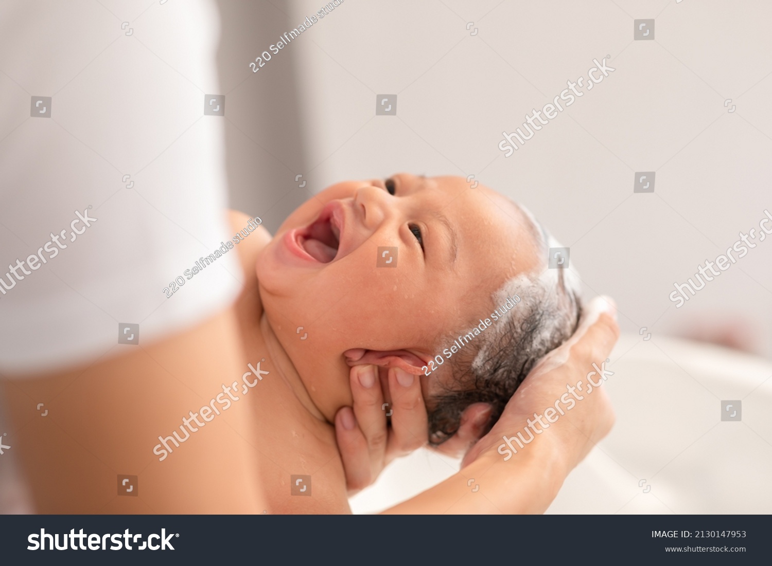 Close up asian newborn baby bathing in bathtub. mother bathing her son in warm water. Happy adorable newborn infant smile in tub relax and comfortable good moment with mom. Newborn baby care concept #2130147953