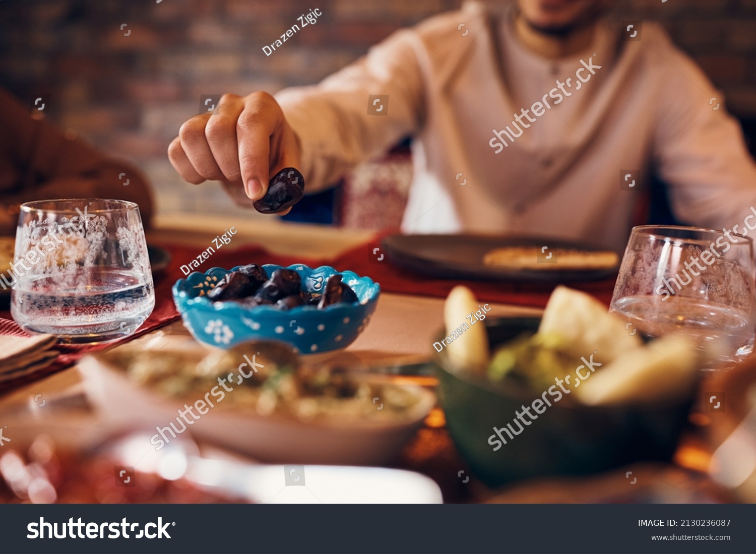 Close-up of Middle Eastern man eating date during Ramadan meal at home.  #2130236087