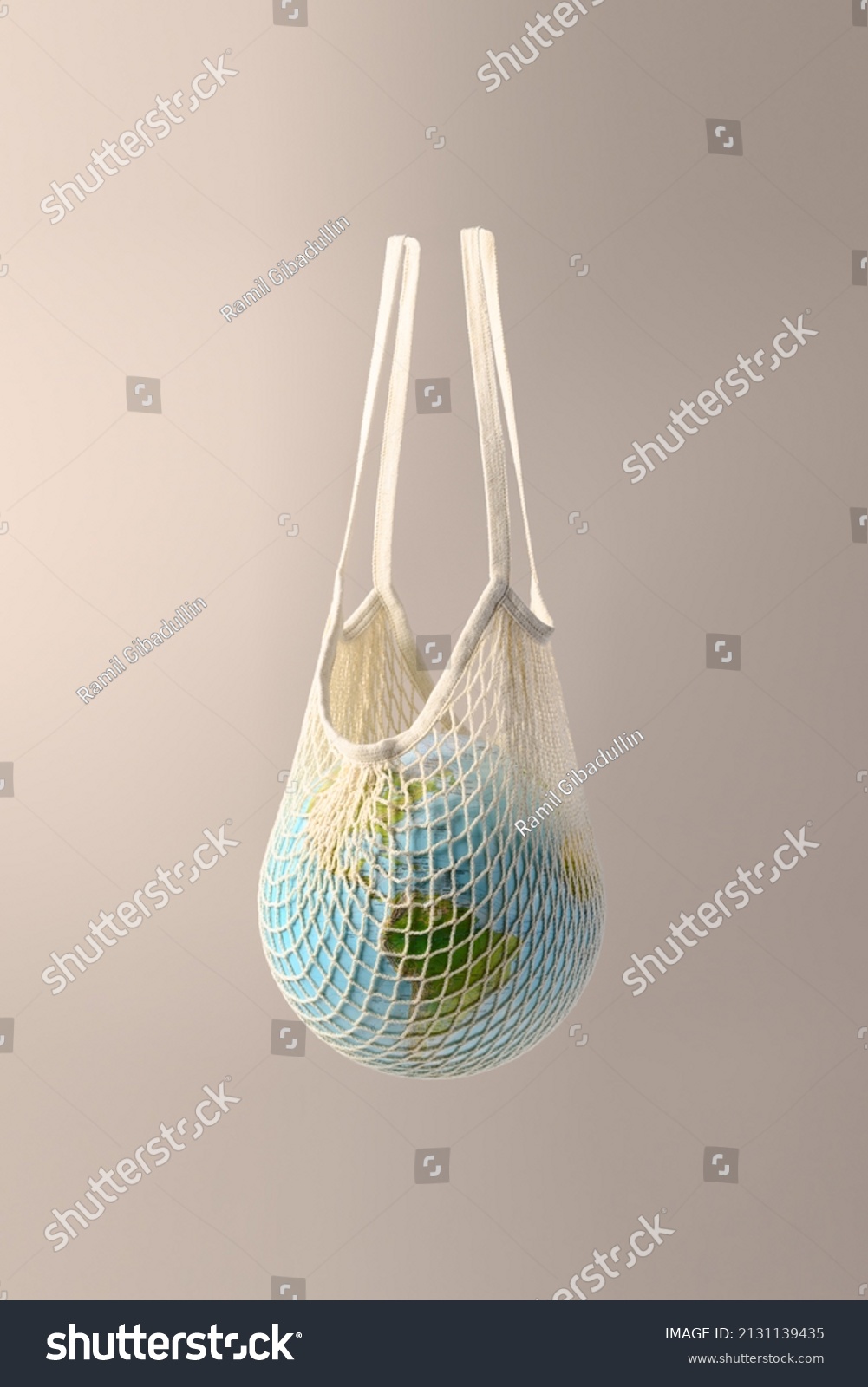 World globe in crochet bag, floating in air on beige background. Eco-friendly life in the style of zero waste. Earth day, save the planet. #2131139435