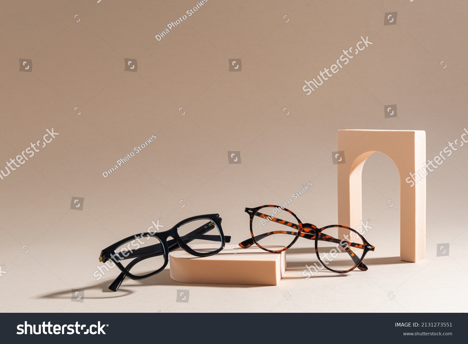 Two pairs of eyelass frames on beige background. Minimalism, summer fashion concept. Trendy eyeglasses still life in minimal stile. Optic store discount, sale. Copy space for text #2131273551