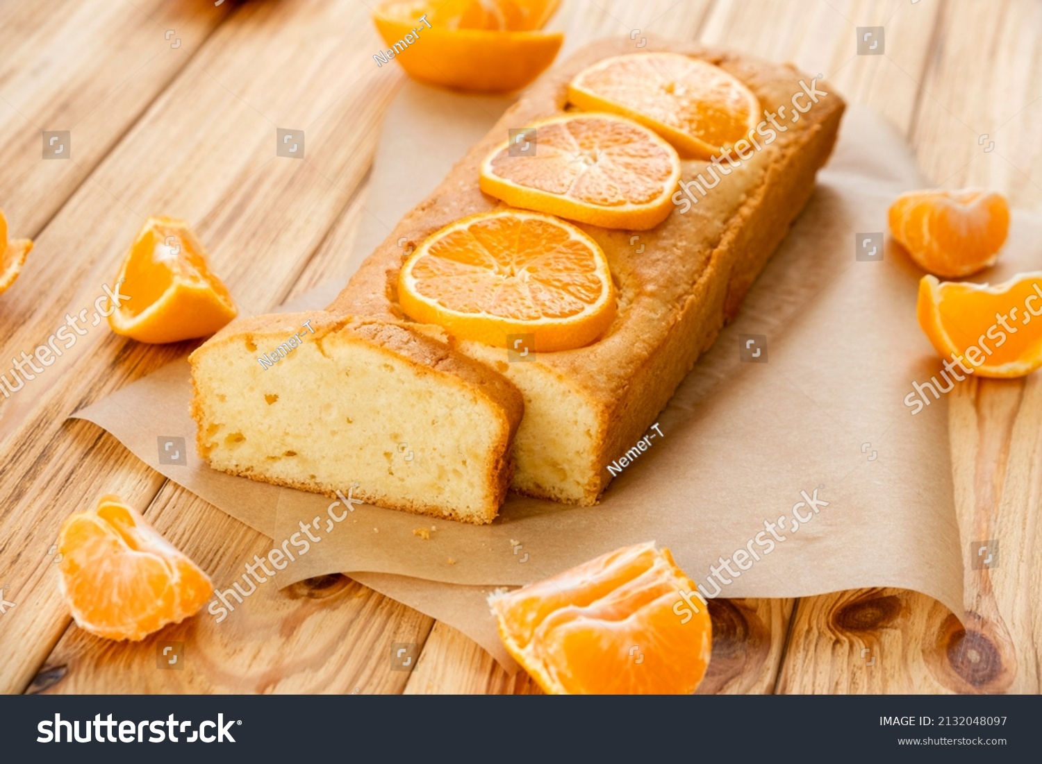 Moist orange fruit pound cake on parchment on rustic wooden background with slices of orange. Delicious breakfast, traditional English tea time. Reciepe of orange pie loaf. #2132048097