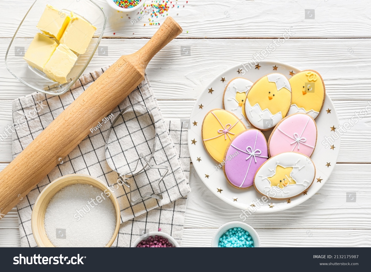 Plate with tasty Easter cookies and ingredients on white wooden background #2132175987