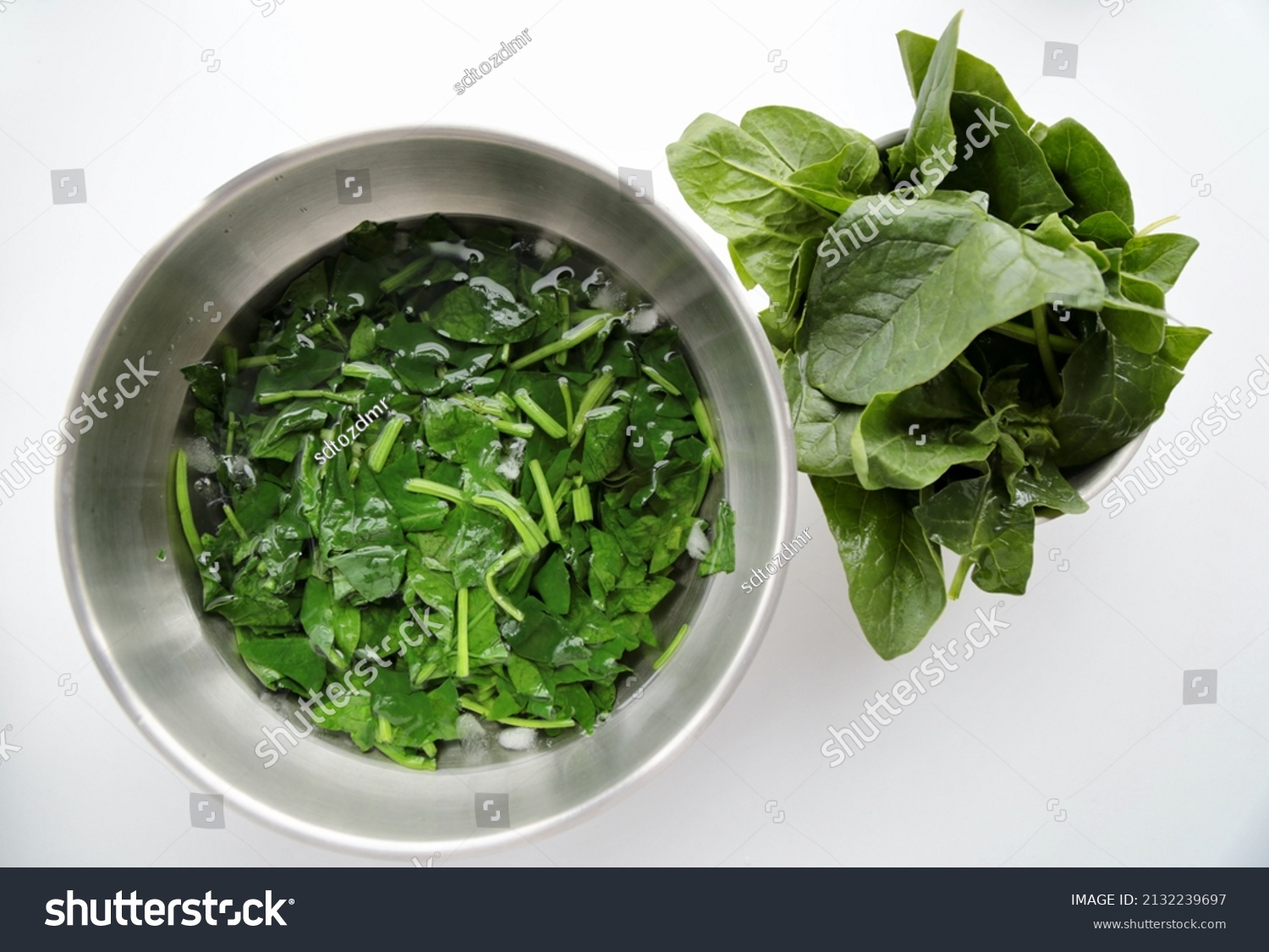 Raw and boiled spinach on a white background. shocking was done in ice water. blanching #2132239697