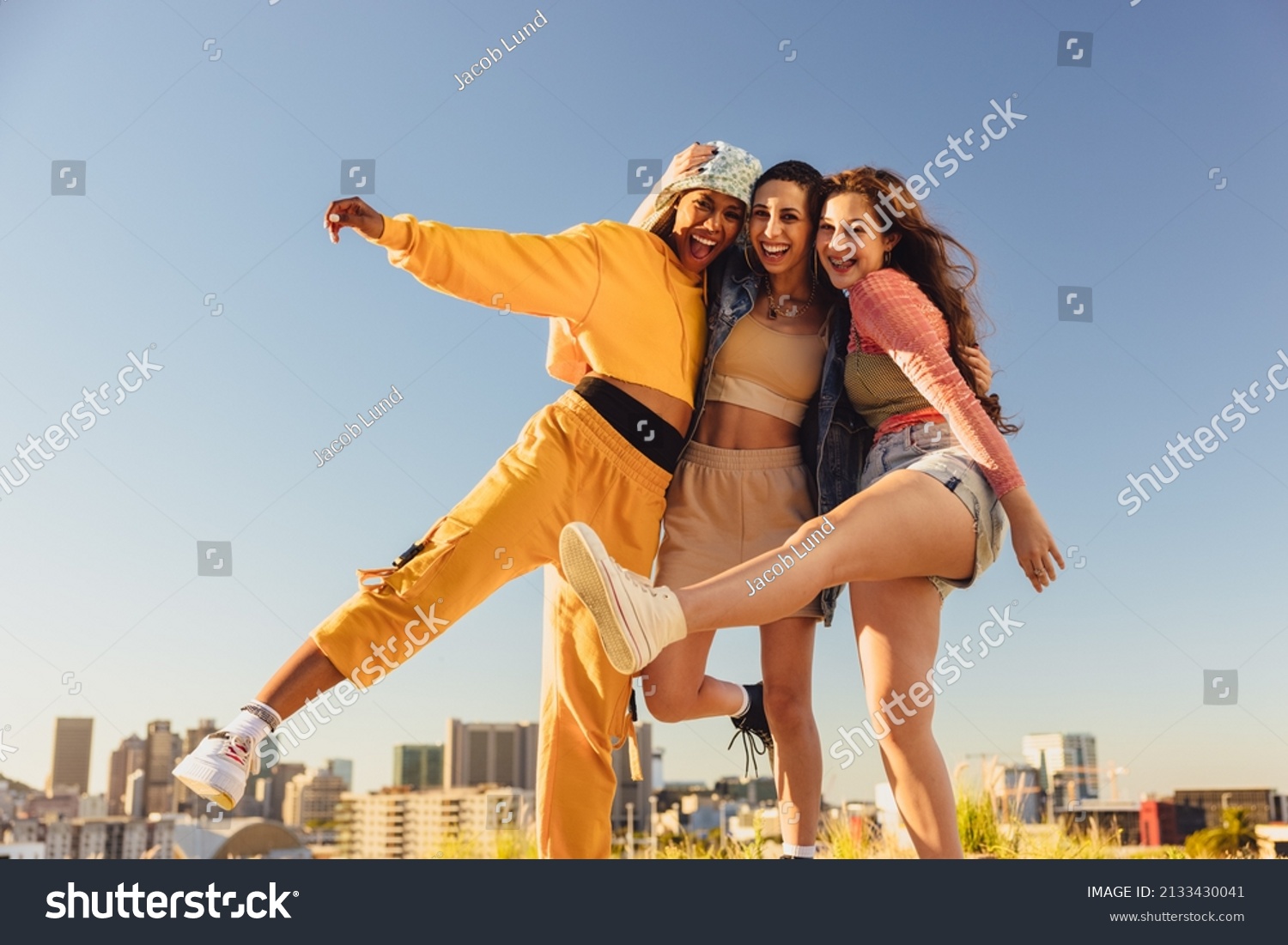 Living life to the fullest. Cheerful female youngsters smiling and having fun while standing together outdoors. Group of generation z friends making happy memories together. #2133430041