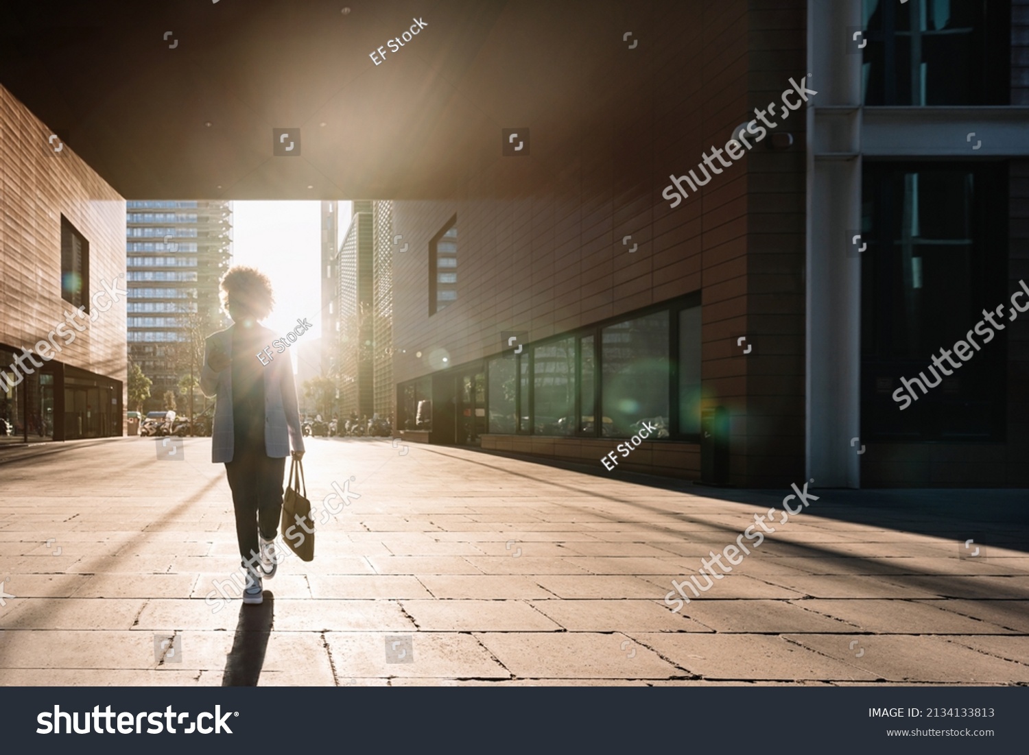 Silhouette of Black business woman walking in a financial district in the city using phone going to office work. Concept of inspiration, enthusiasm, start-up, feminism #2134133813