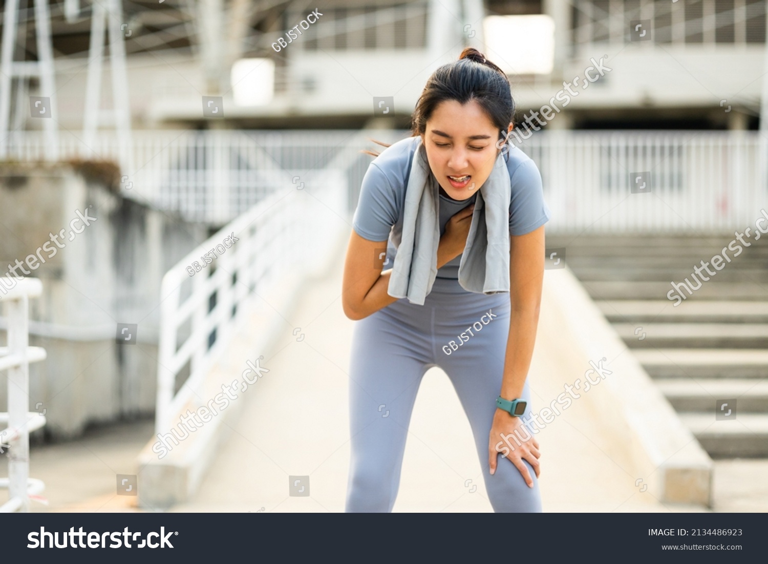 Beautiful woman tired during jogging in the city at sunrise. Young asian female intense training workout challenge breathing exhausted. Exercise in the morning. Healthy and active lifestyle concept. #2134486923