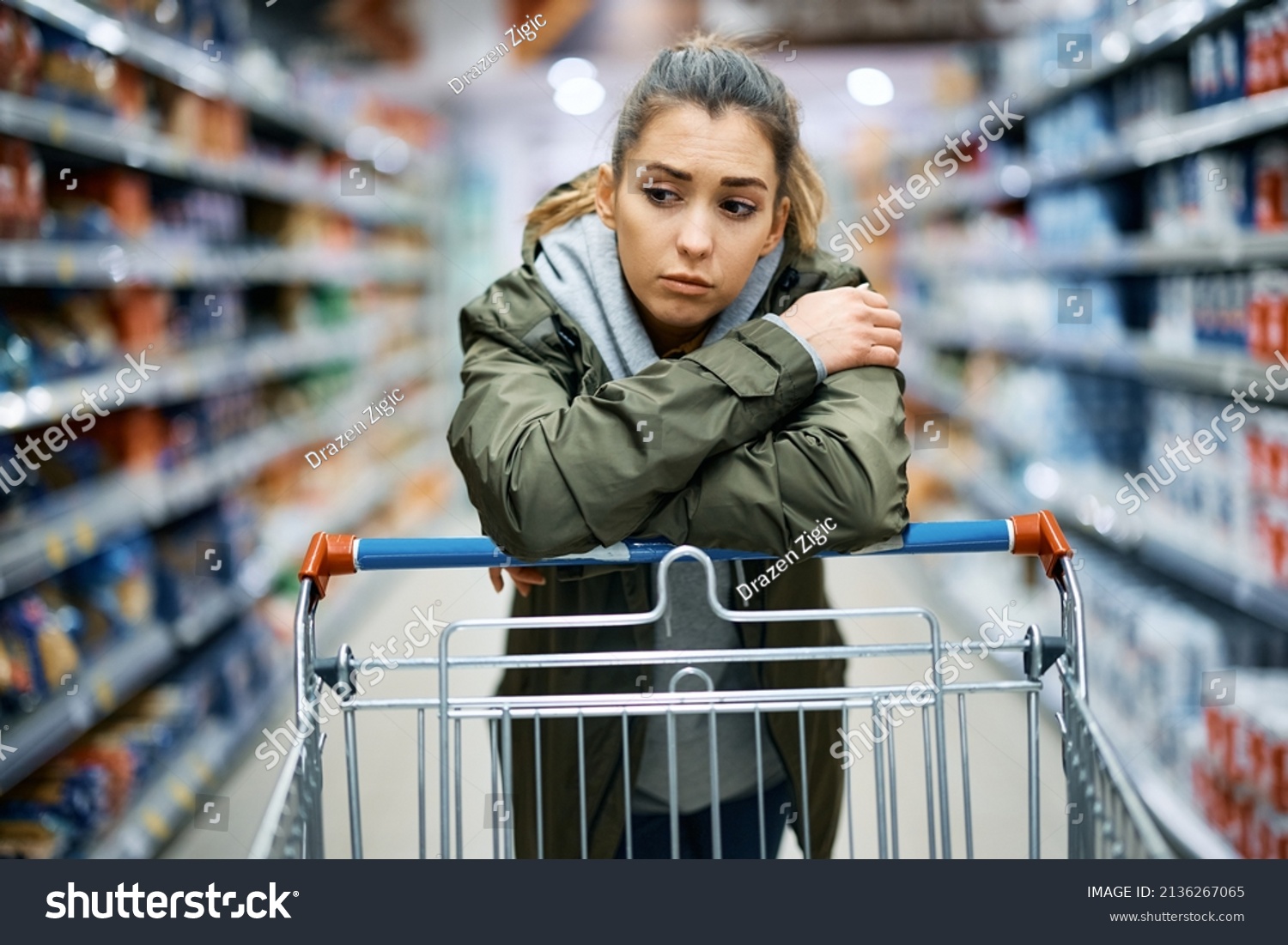 Young woman buying in supermarket and feeling worried about increase in food prices.  #2136267065