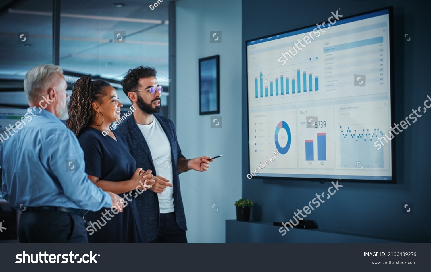 Company Operations Manager Holds Meeting Presentation. Diverse Team Uses TV Screen with Growth Analysis, Charts, Statistics and Data. People Work in Business Office. #2136489279