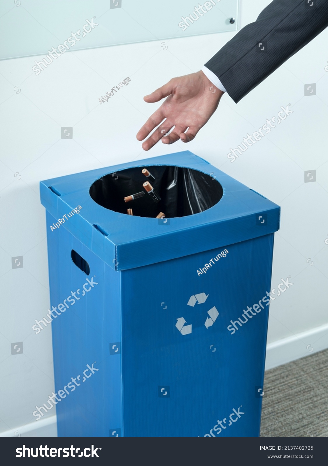 Mans hand throws the batteries into a special trash can for the separate collection of hazardous waste. Environment ecology concept. Illustrative editorial.  #2137402725