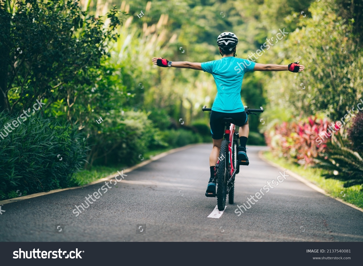 Woman feel free cycling on tropical park trail in summer #2137540081