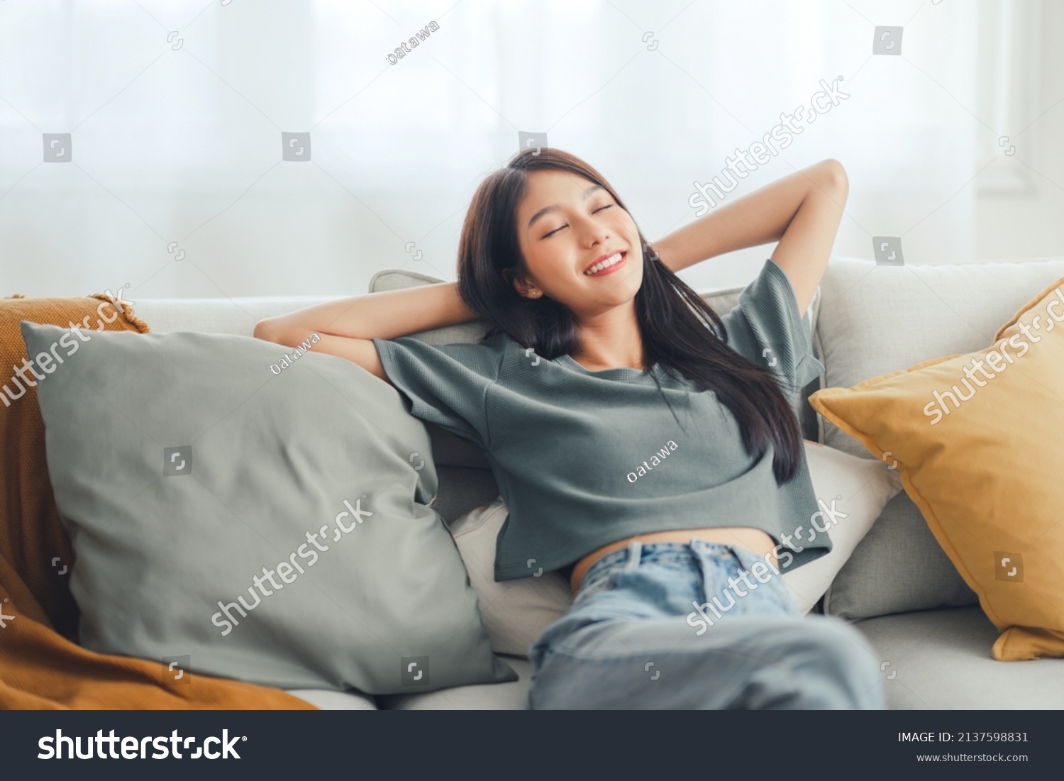 Relaxed young asian woman enjoying rest on comfortable sofa at home, calm attractive girl relaxing and breathing fresh air in home, copy space. #2137598831