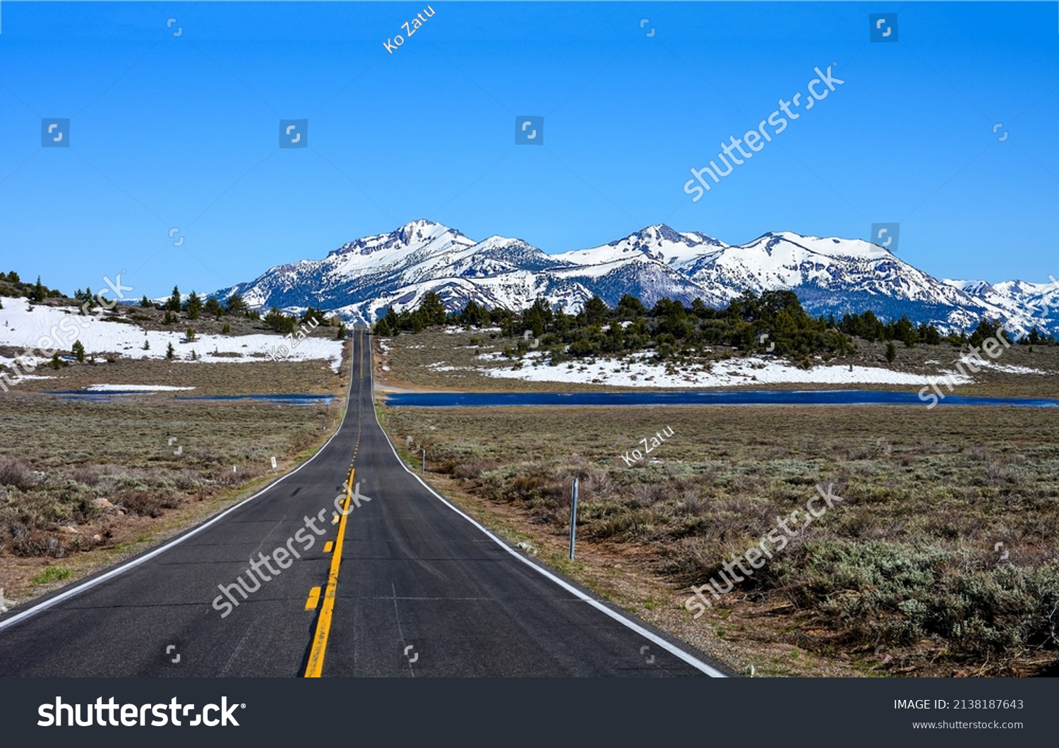 The road through the valley to the snow capped mountains. Mountain valley road landscape. Snowy mountain valley road way #2138187643