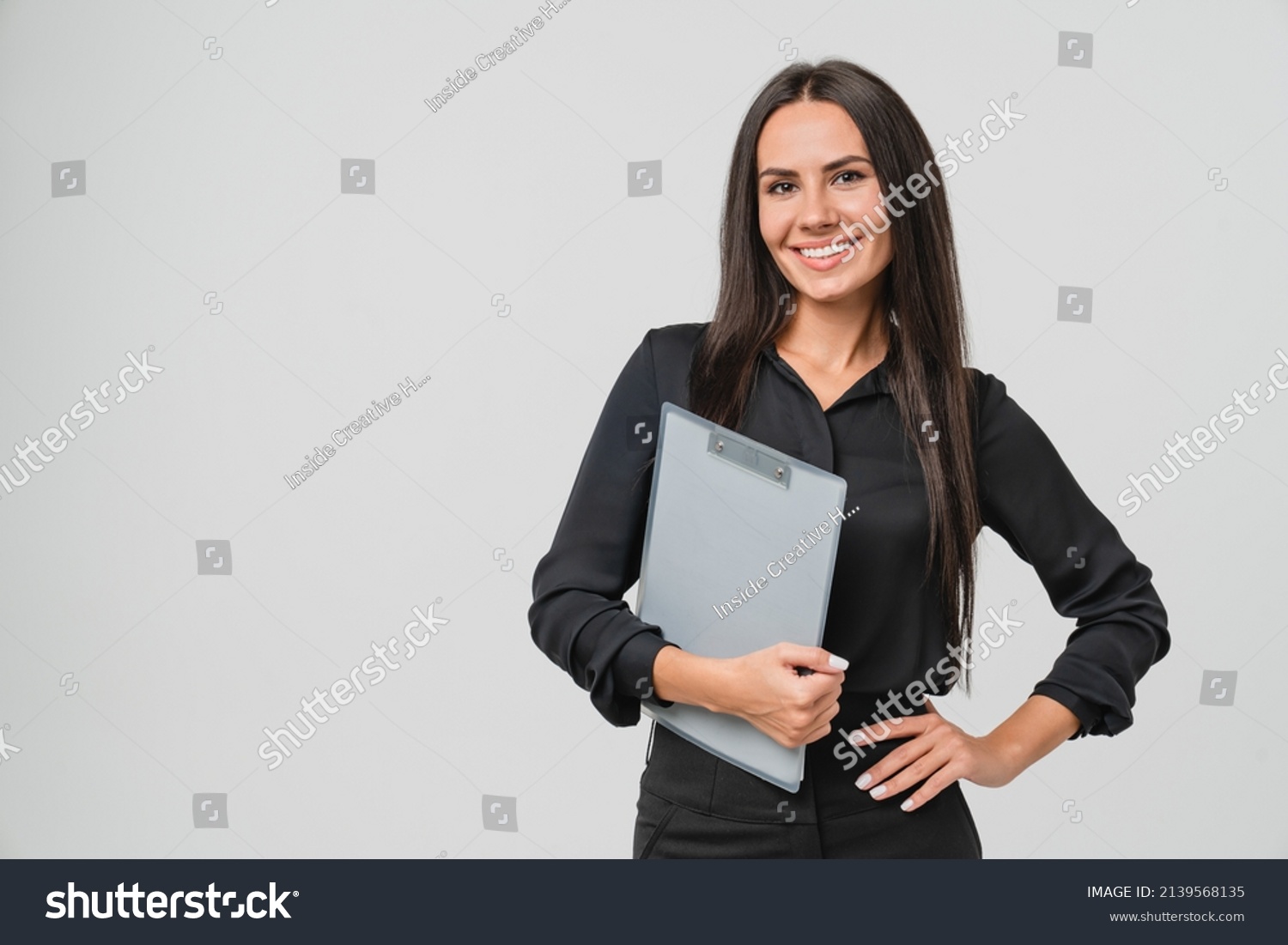 Female young businesswoman auditor inspector examiner controller in formal wear writing on clipboard, checking the quality of goods and service looking at camera isolated in white background #2139568135