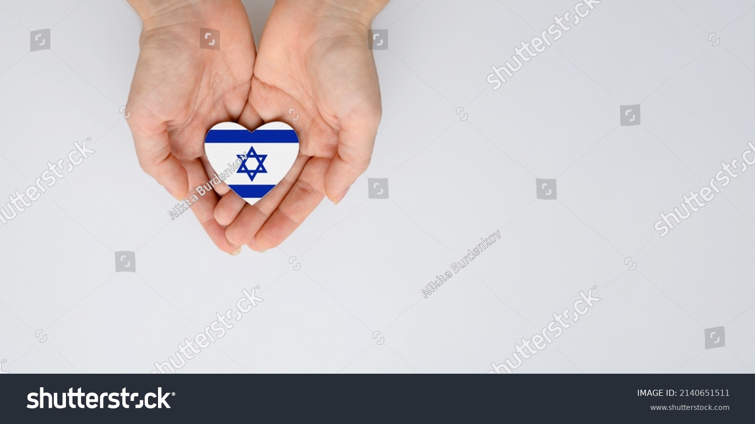 The national flag of Israel with the coat of arms in female hands. Flat lay, copy space. #2140651511