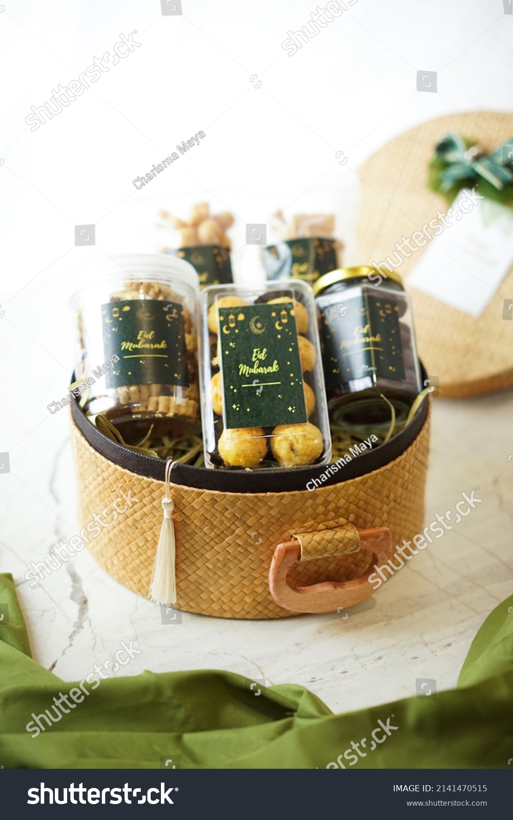 Ramadhan gift. Hampers moslem theme for celebrete the holy, bake snack, nastar, bakery, cookies, pudiing, chococips, roll cake, castangel.with greeting card and green accessories on white background #2141470515
