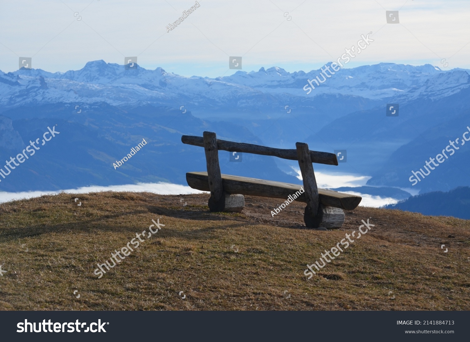 A bench on top of the mountain Rigi in Switzerland overlooking the skyline of mountaintops and lake in Switzerland #2141884713