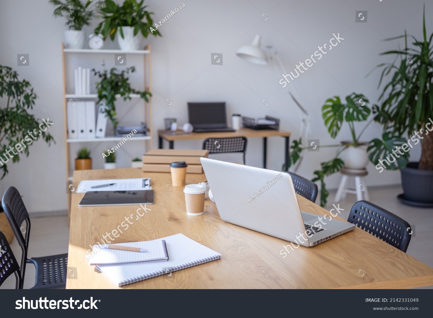 Laptop computer standing on wooden desk in workspace with different devices nearby. No people at the office. Stock photo  #2142331049