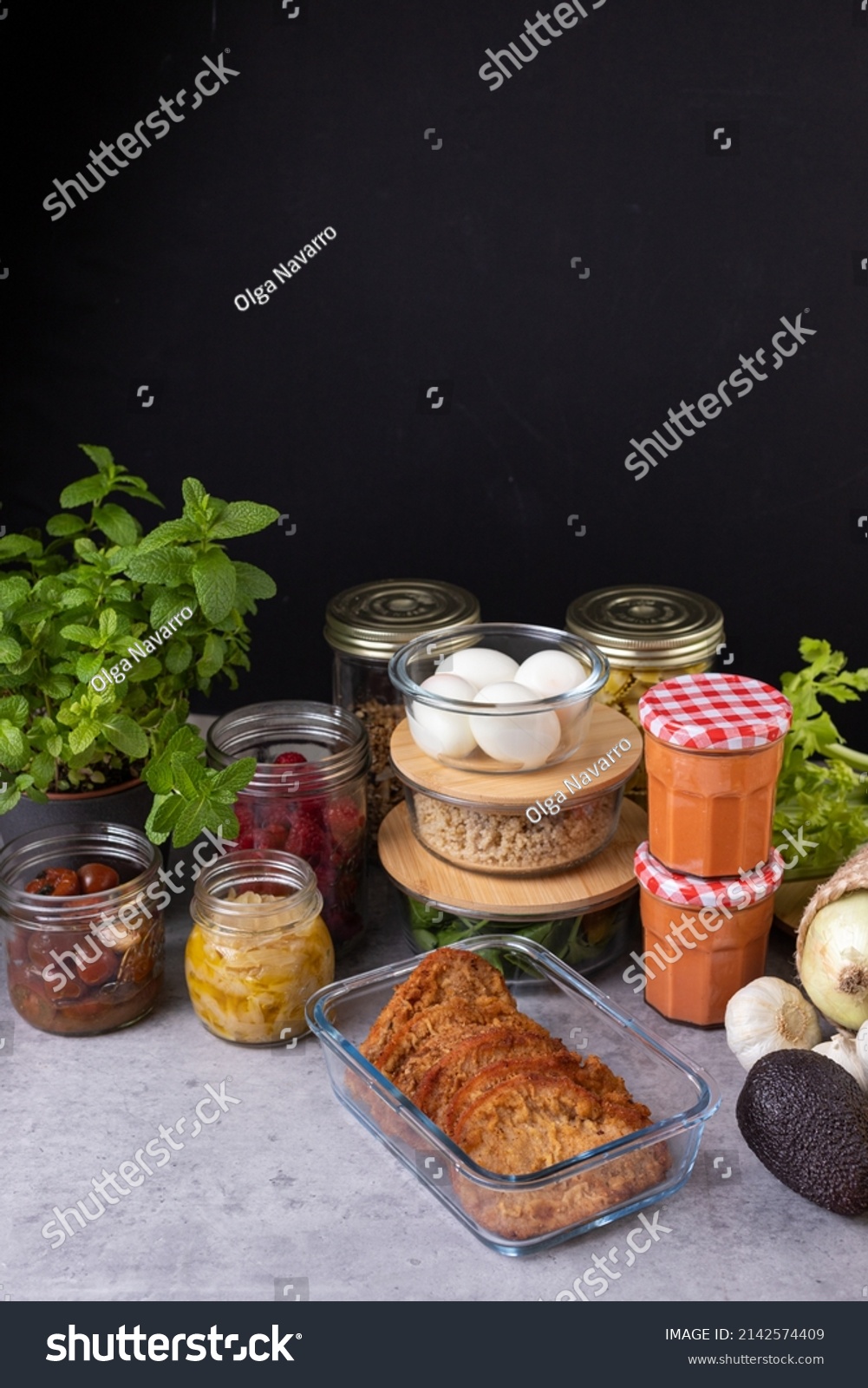 Complete batch cooking scene with several piles of glass containers full of homemade food with a dark copy space background. #2142574409
