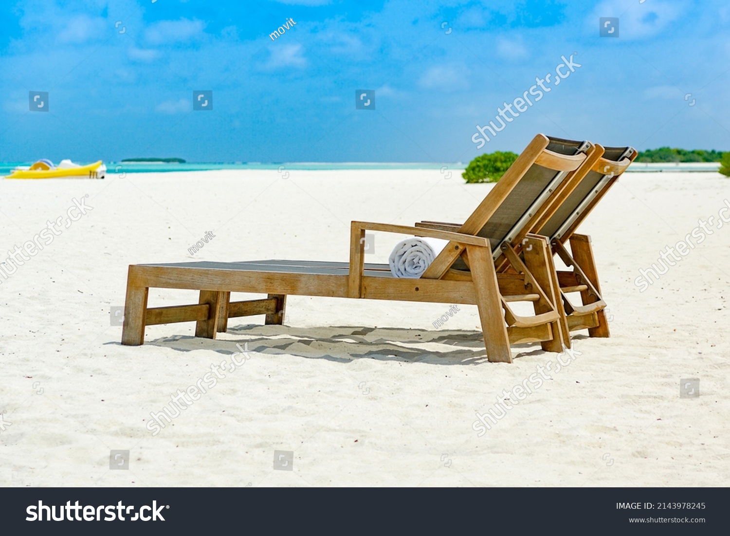Two beach chairs side by side on sandy ocean front with view over blue sea, shallow depth of field #2143978245
