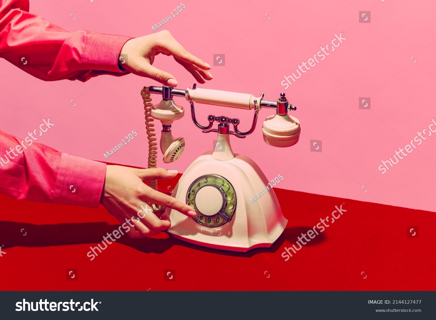 White telephone, Pop art photography. Retro objects, gadgets. Female hand holding handset of vintage phone isolated on pink and red background. Vintage, retro 80s, 70s style. Complementary colors. #2144127477