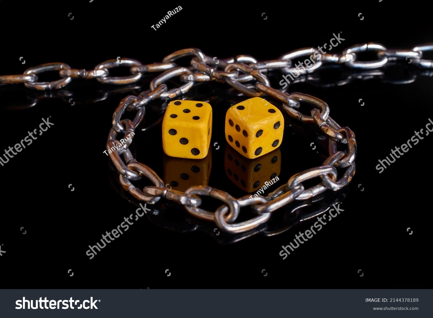 Gambling addiction. Two dice wrapped in a chain on a black background with reflection. Selective focus #2144378189