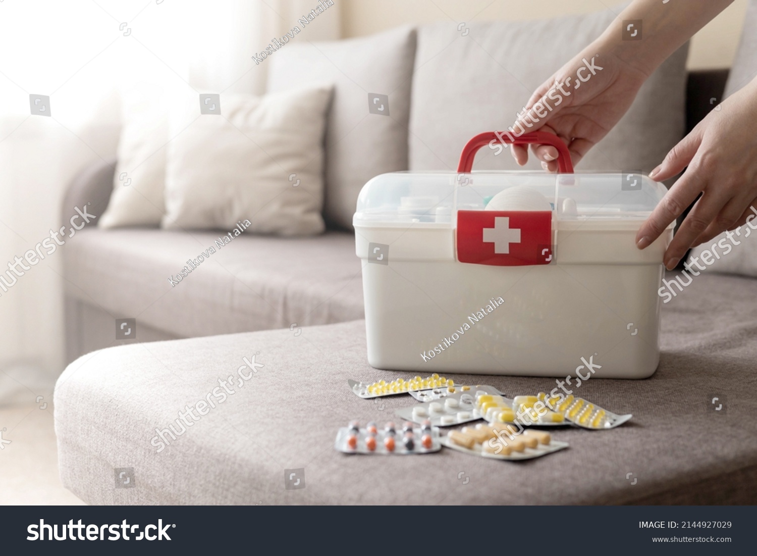 Closeup female hand neatly placing medicament at domestic first aid kit top view. Storage organization in transparent plastic box drug, pill, syringe, bandage. Fast health help safety emergency supply #2144927029