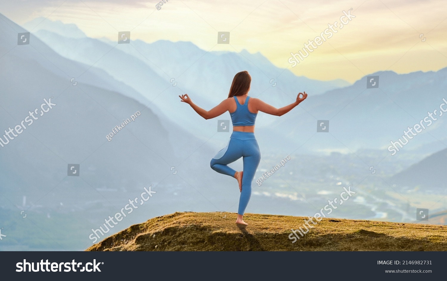 Back view of free calm serene blissful satisfied fitness woman doing yoga exercise on top rock against idyllic morning mountain view. Mental mind care and healthy habits #2146982731