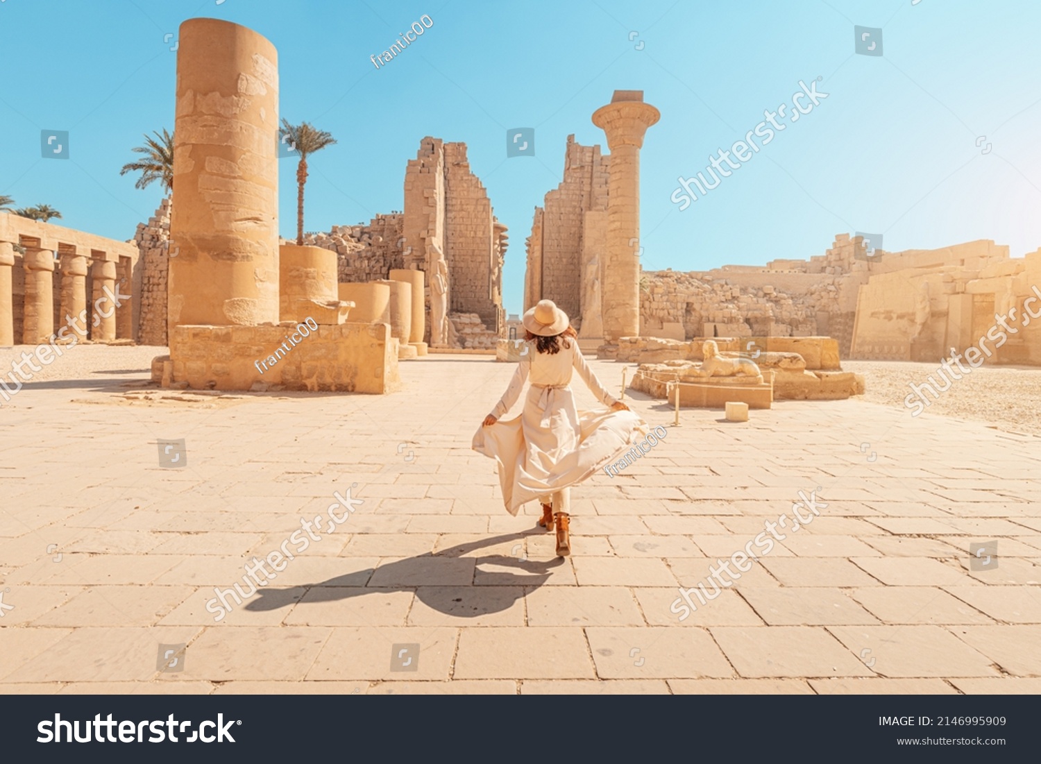 Happy woman traveler explores the ruins of the ancient Karnak temple in the heritage city of Luxor in Egypt. Giant row of columns with carved hieroglyph #2146995909
